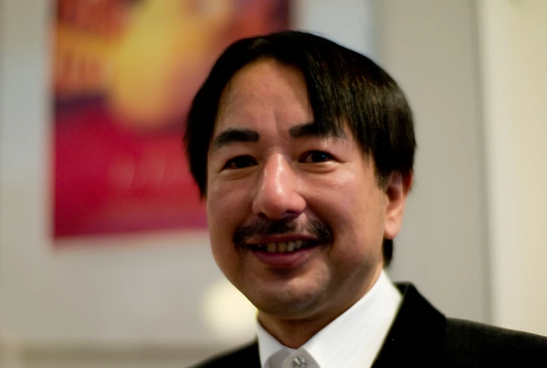 a man in a black suit and white shirt smiling