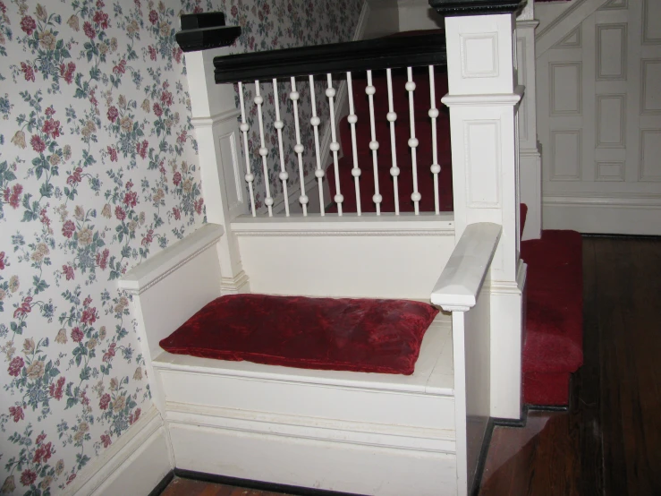 a very small white bench with red cushion