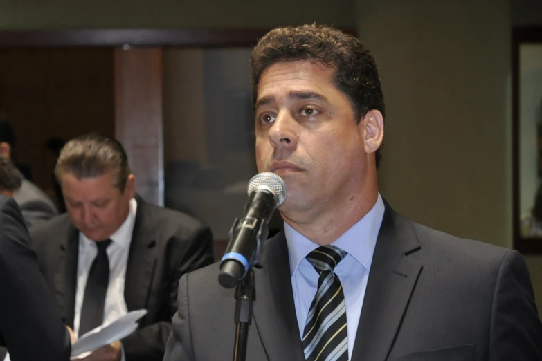 a man speaking into a microphone in a suit