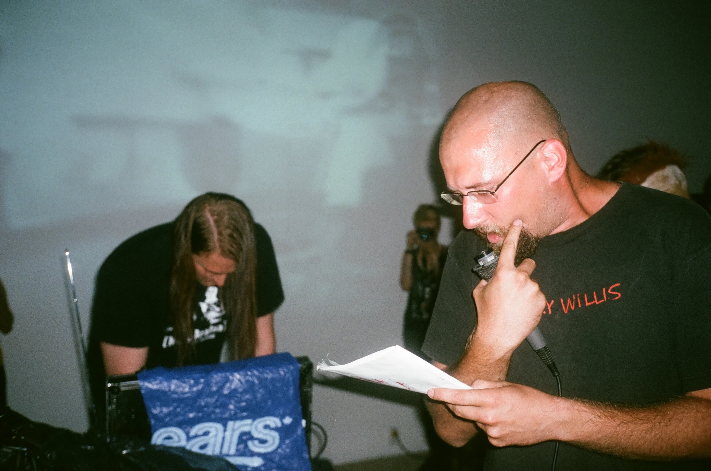 a man in black shirt using phone with other people behind him