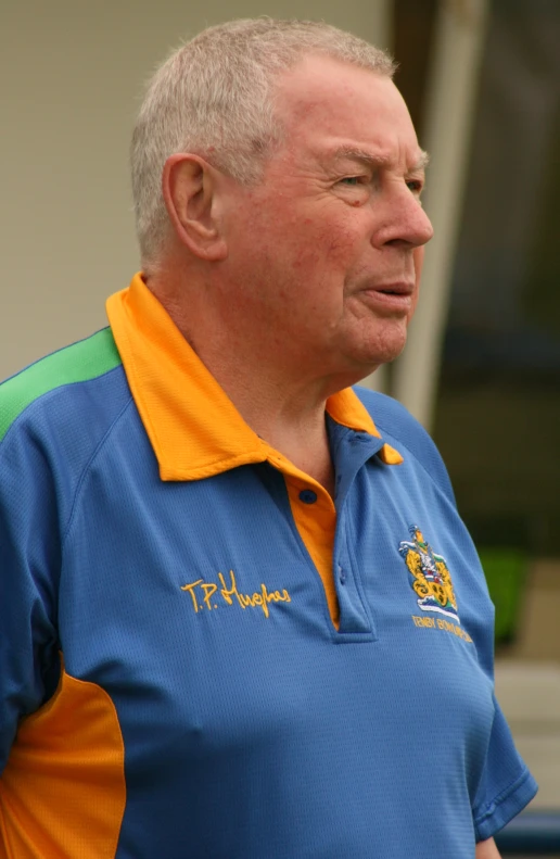 an older man with his eyes closed wearing a blue and yellow polo shirt