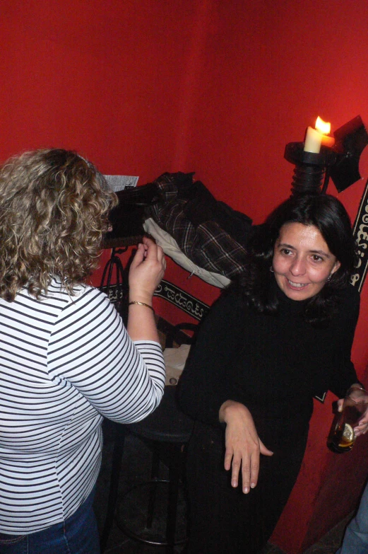 two women are sitting near a red wall