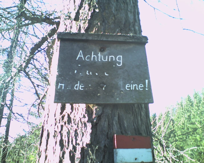 there is a sign attached to a tree with the words achtung