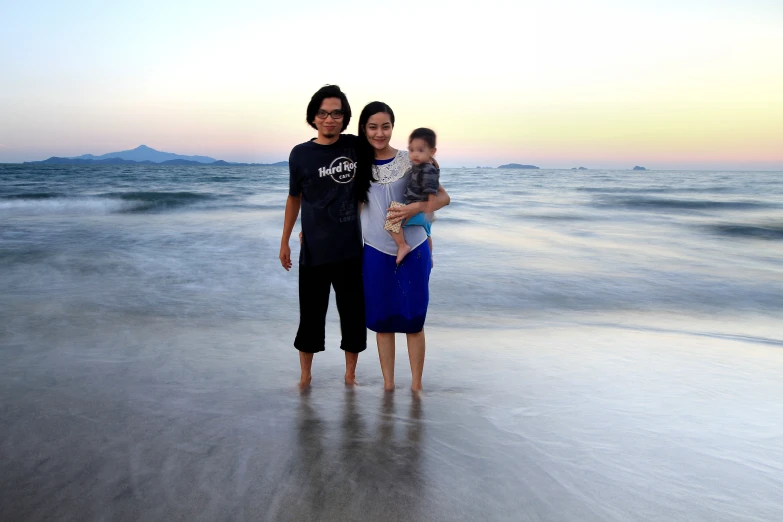 the woman, a man and their child are standing in the surf