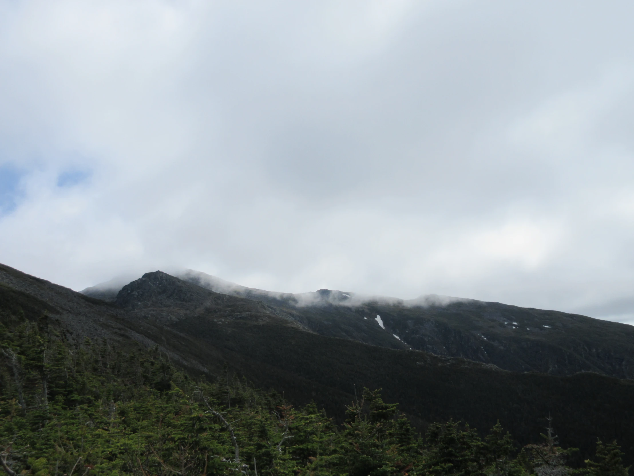 clouds are rising above the mountains in the background