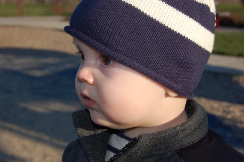 the young child is wearing a striped hat