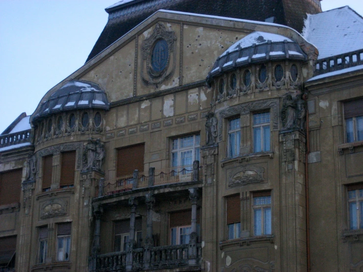 a building has snow on its roof and balcony