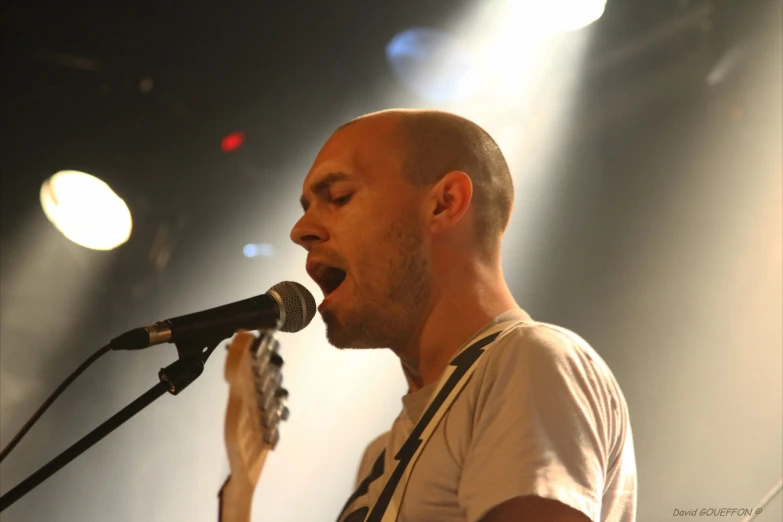 a man singing into a microphone while holding an electric guitar