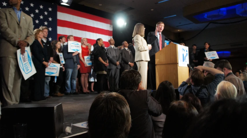 people are standing on stage and holding signs