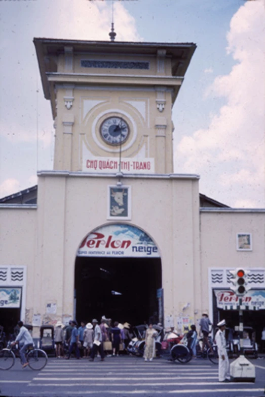 a busy street with people crossing the street in front of an entrance to the train station