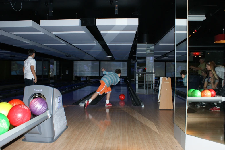 an indoor bowling alley with people playing and bowling on balls