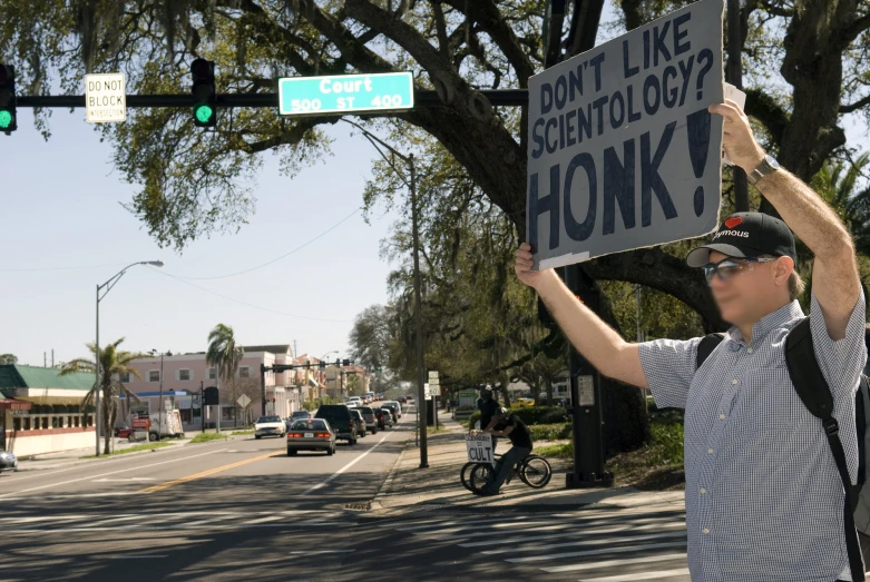 a man with his hands up holding a sign that reads don't like the catholic or honk?