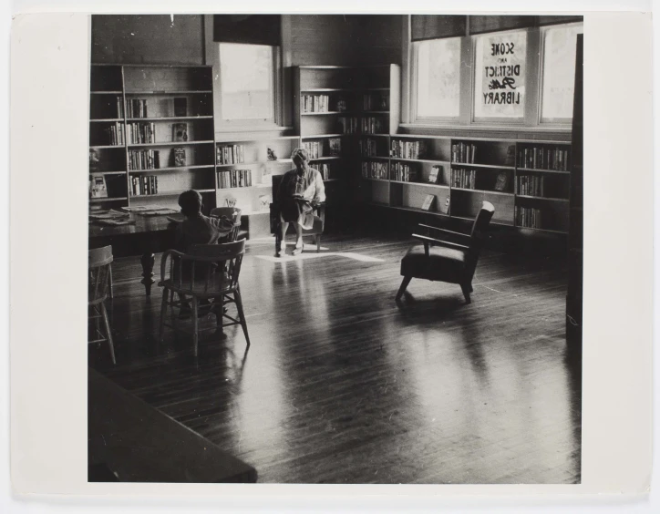 two children playing in a large room with bookcases