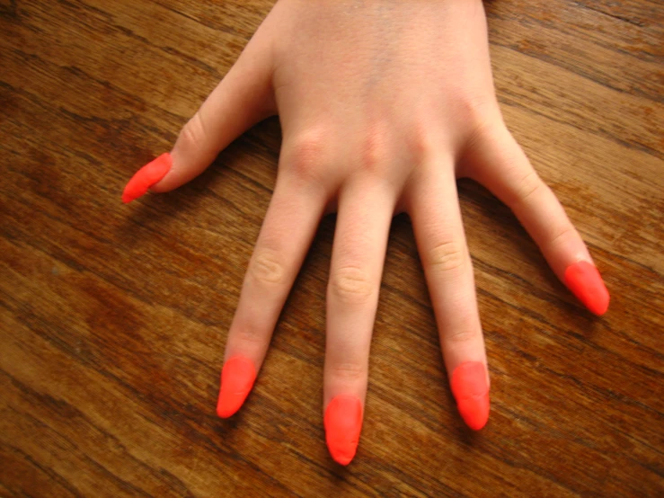 a hand with neon red nail polish on it