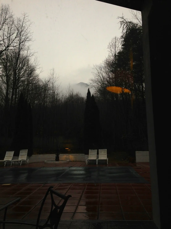 two chairs sitting by an outside table looking out on to a misty forest