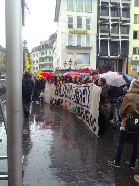 a group of people standing on the sidewalk under umbrellas