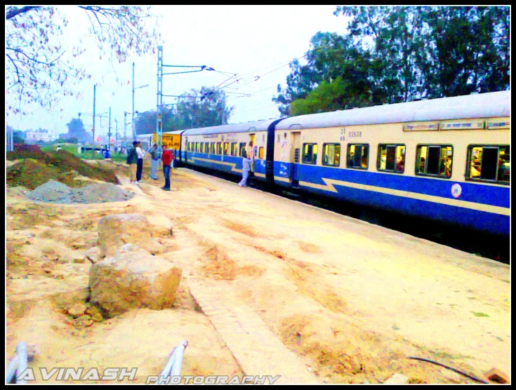 a yellow train is traveling past people