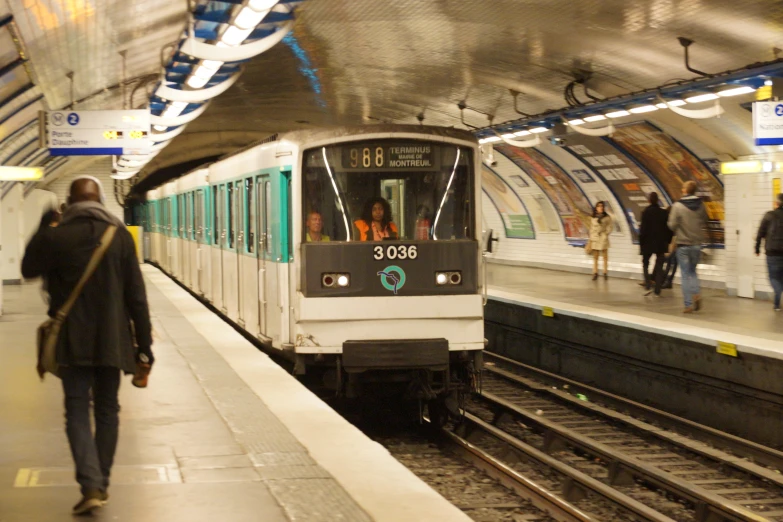 a commuter train pulling into a station where people walk