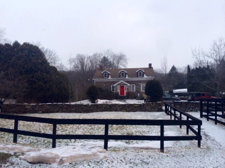 a snow covered yard with fence and house in the distance