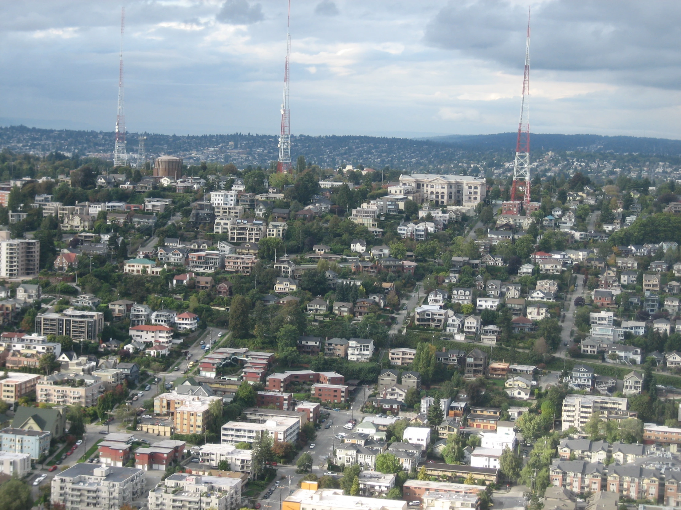 city with trees, buildings and a cell tower in the distance