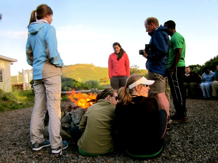 a group of people around a fire pit on a hill side