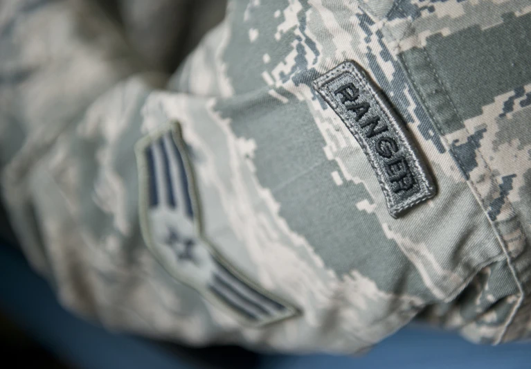 a person's army fatigues has a patch on his chest