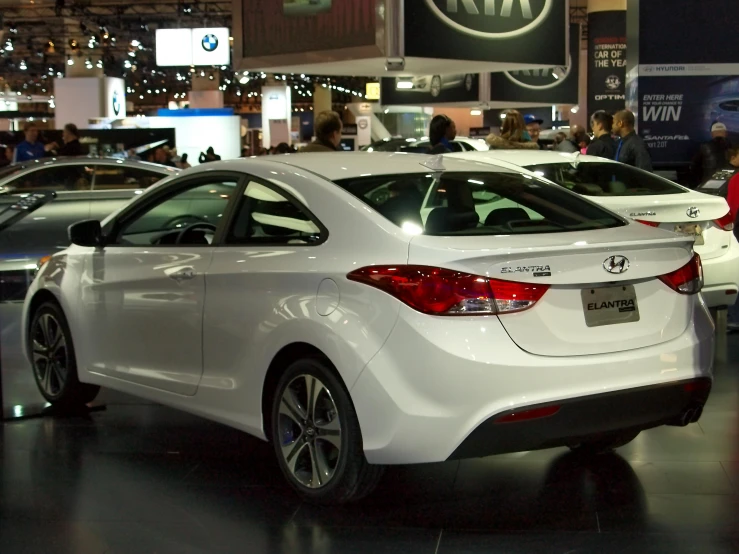 the rear view of a white car is at a show