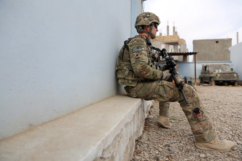 an army member sitting on the wall near a building