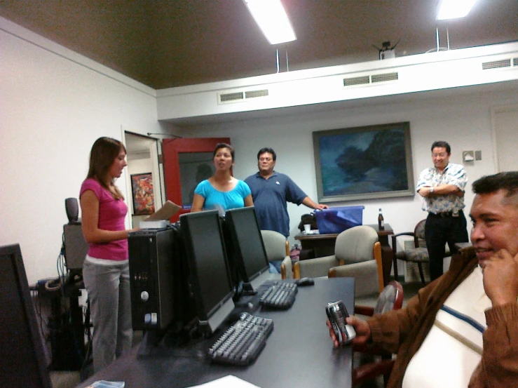 group of people gathered around a desk working on their computers