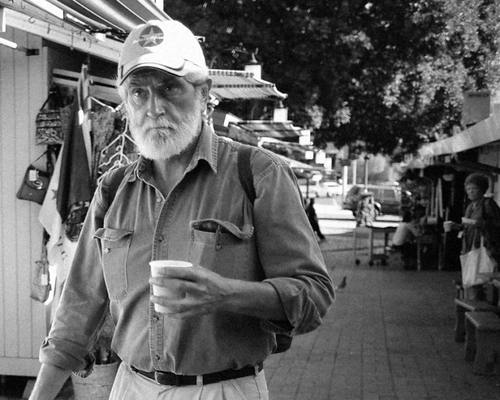 a man wearing a hat and holding a cup