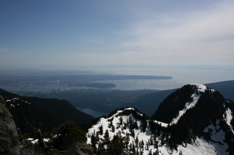 a mountain peak with snow, pine trees, and a lake