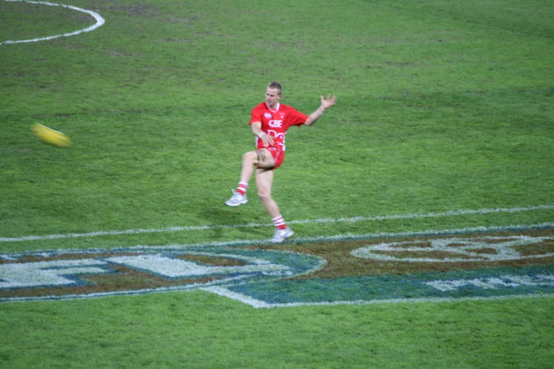 a young woman tossing a yellow frisbee at a football game