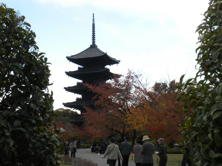 people walking in front of an oriental pagoda at the park