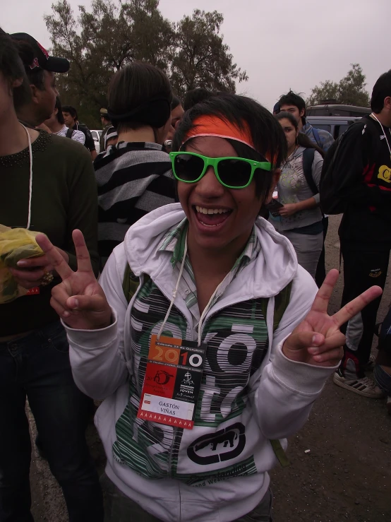 a woman wearing sunglasses smiles in front of an outdoor crowd