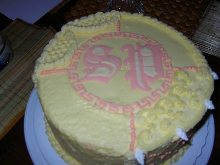 yellow cake with ornate red monogram on it