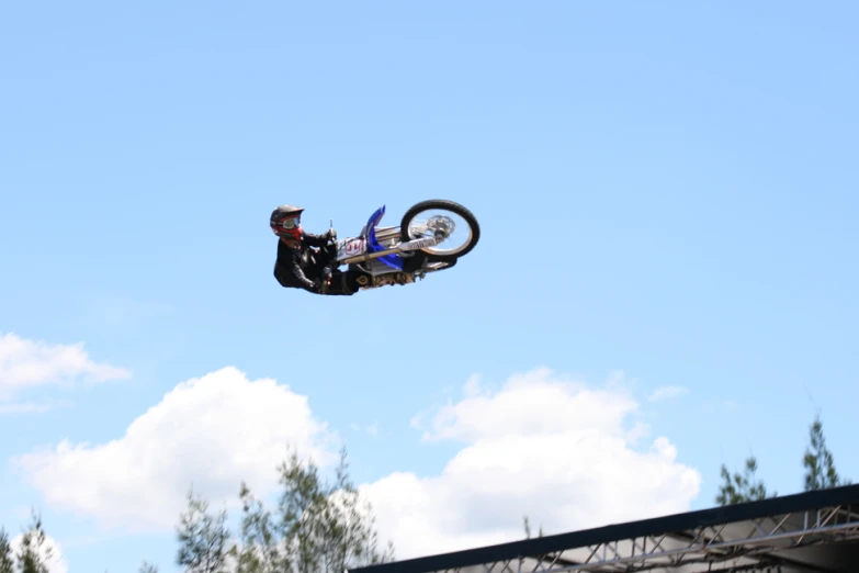 a man doing tricks on a motorcycle over a hill