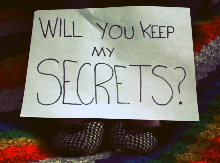 a person holding a sign that says will you keep my secrets?