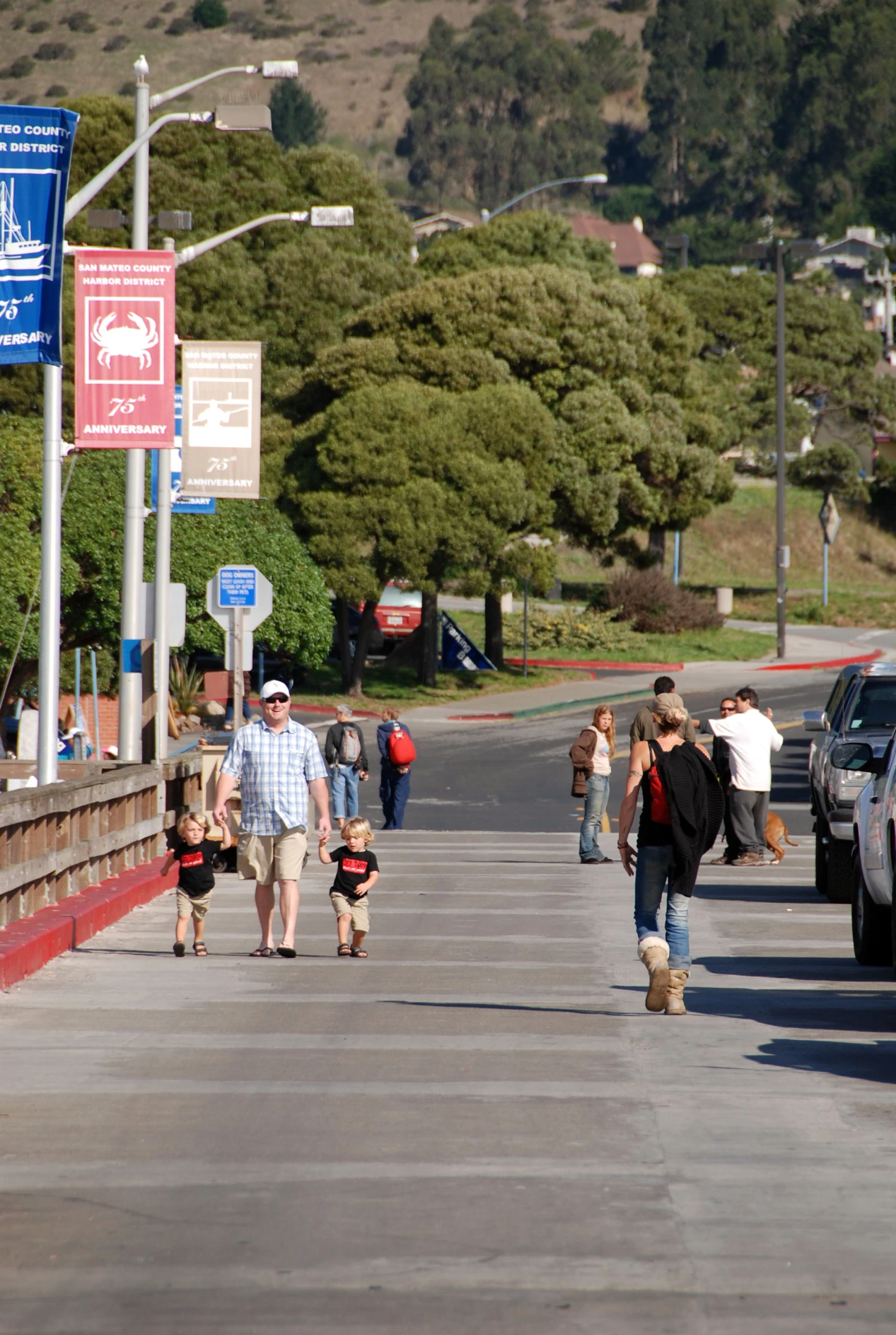 several people are walking on the street next to cars