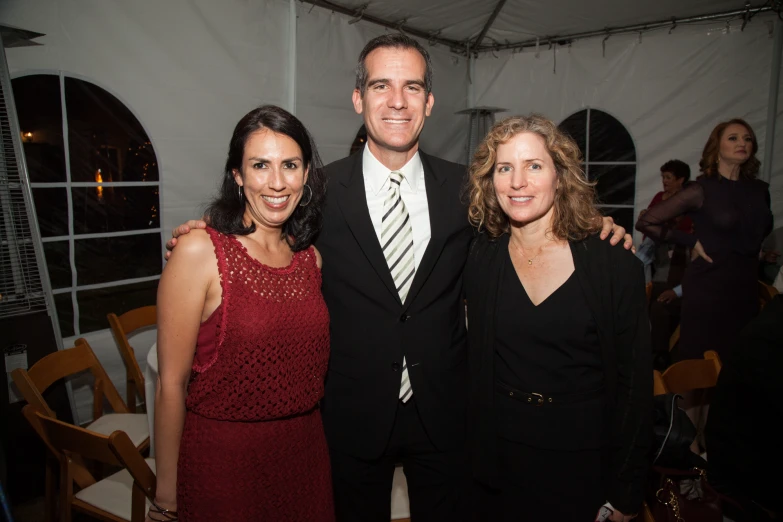 three people posing for the camera in front of a white tent