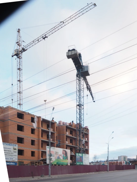 a view from across the street of a city street with two crane lifts