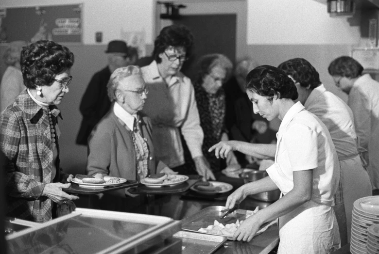 several people at a counter making food from plates