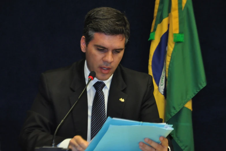 a man in a suit and tie sits at a microphone