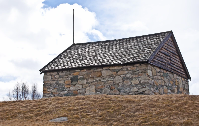 a house made out of logs sitting on top of a hill