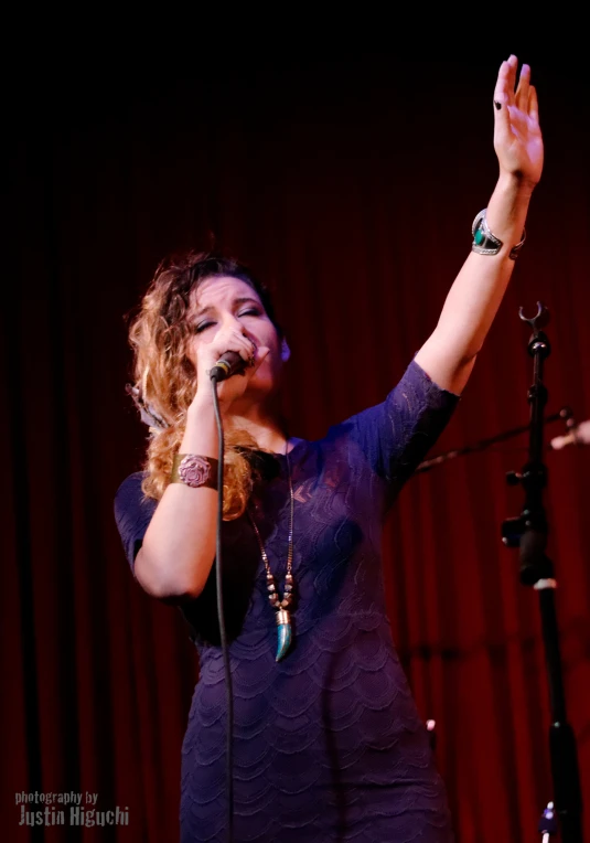 a woman in purple dress holding her hands up with one hand