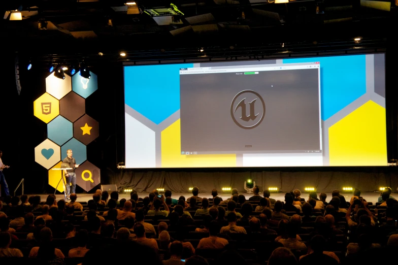 a man is speaking at the convention with an impressive screen