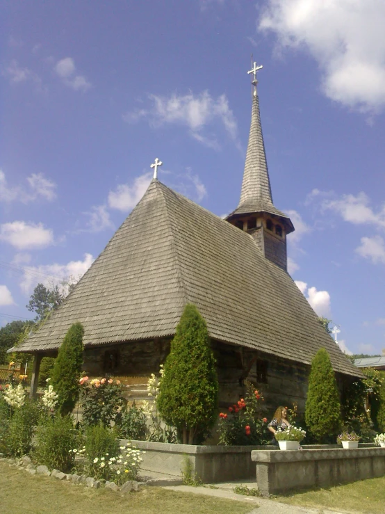 a church with a clock tower surrounded by flowers and shrubs