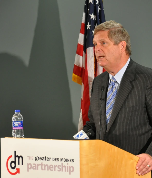 man giving a speech behind a wooden podium