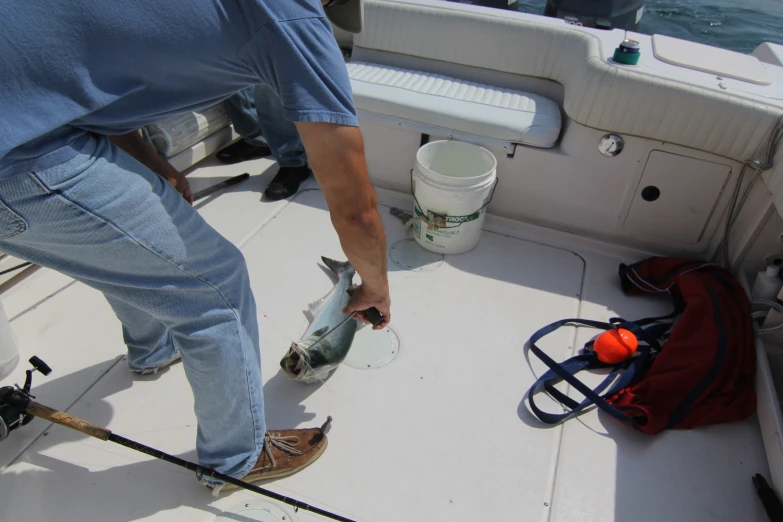 someone is holding a fish with one hand on the boat