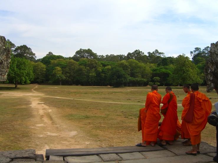 four monks stand next to each other at the edge of a path