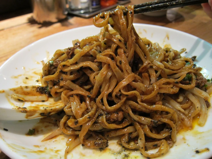 a dish of noodles with sauce and spices being stirred over the top